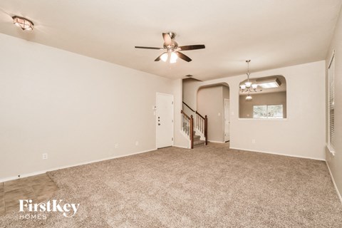 a living room with carpet and a ceiling fan
