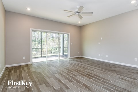 the spacious living room with wood flooring and a ceiling fan