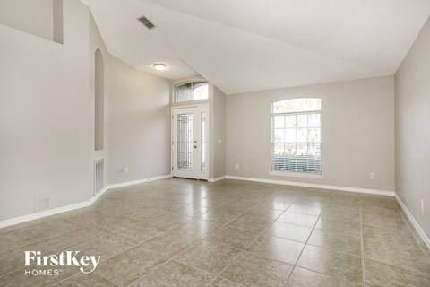 A spacious empty room with tiled flooring and a slanted ceiling.