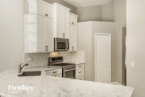 A kitchen with a marble countertop and white cabinets.