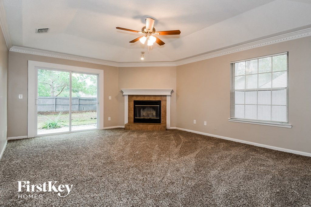 an empty living room with a fireplace and a ceiling fan