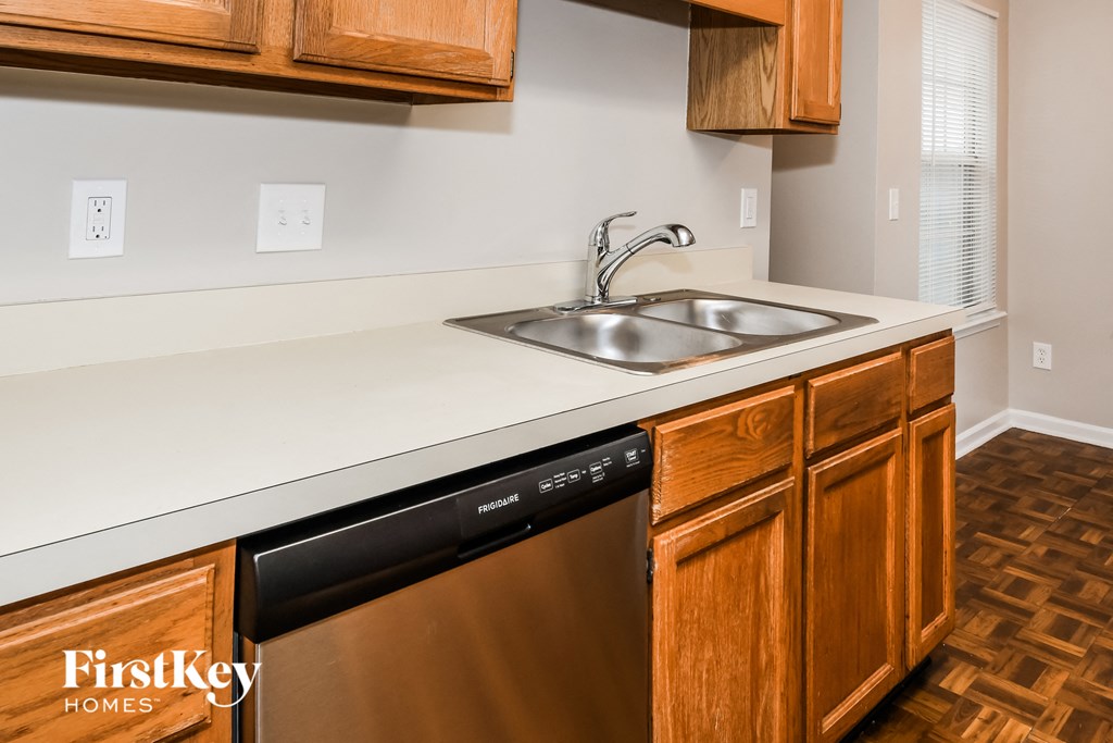 a kitchen with a sink and a dishwasher and wooden cabinets