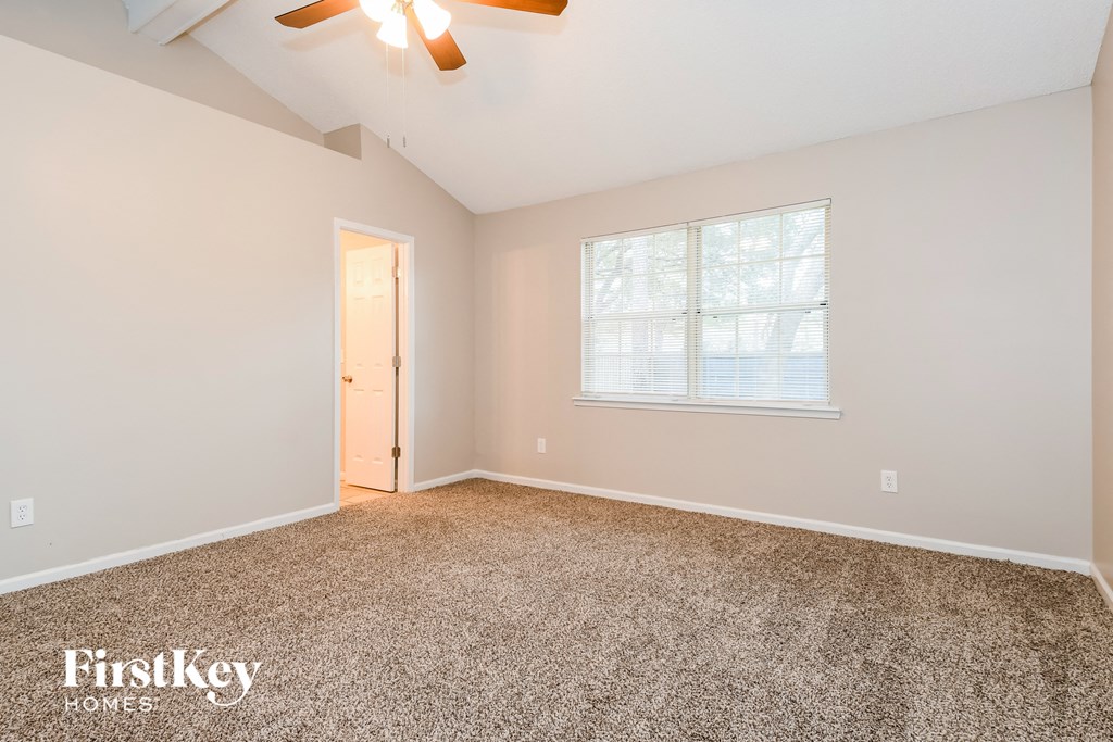 a bedroom with carpet and a window and a ceiling fan