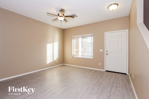 an empty living room with a ceiling fan and a white door