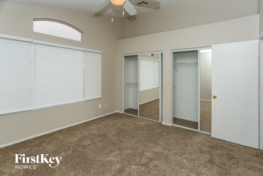 a bedroom with two closets and a carpeted floor and a ceiling fan