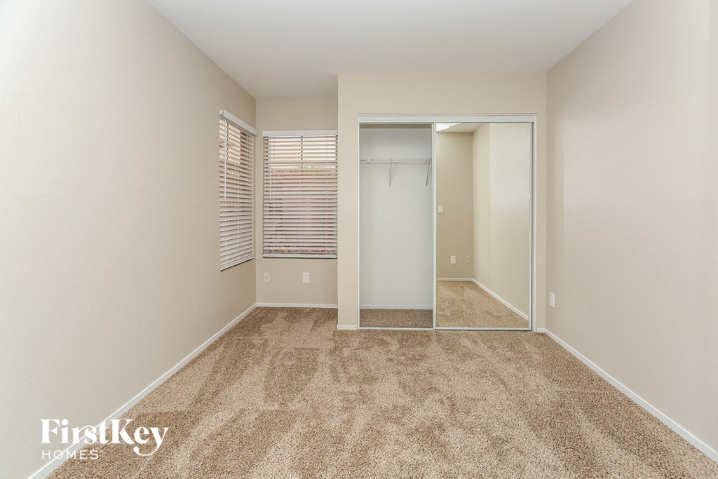 a bedroom with a mirrored closet and a carpeted floor