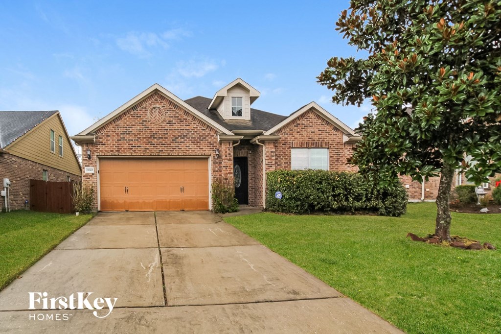 front view of a brick house with a garage and a tree