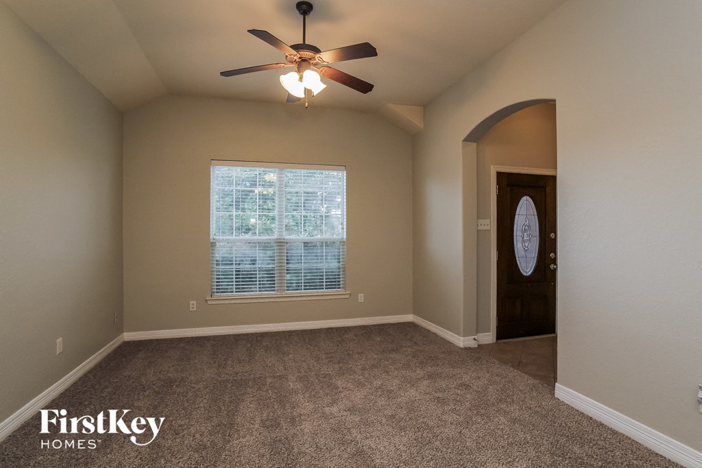 an empty living room with a ceiling fan and a window