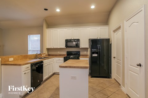 a kitchen with white cabinets and a black refrigerator