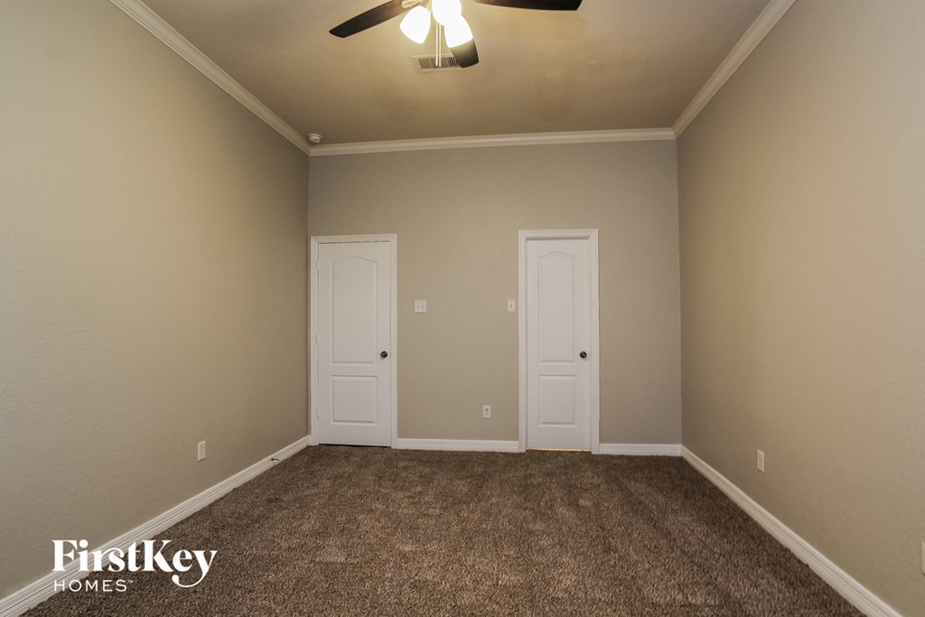 a carpeted room with two doors and a ceiling fan
