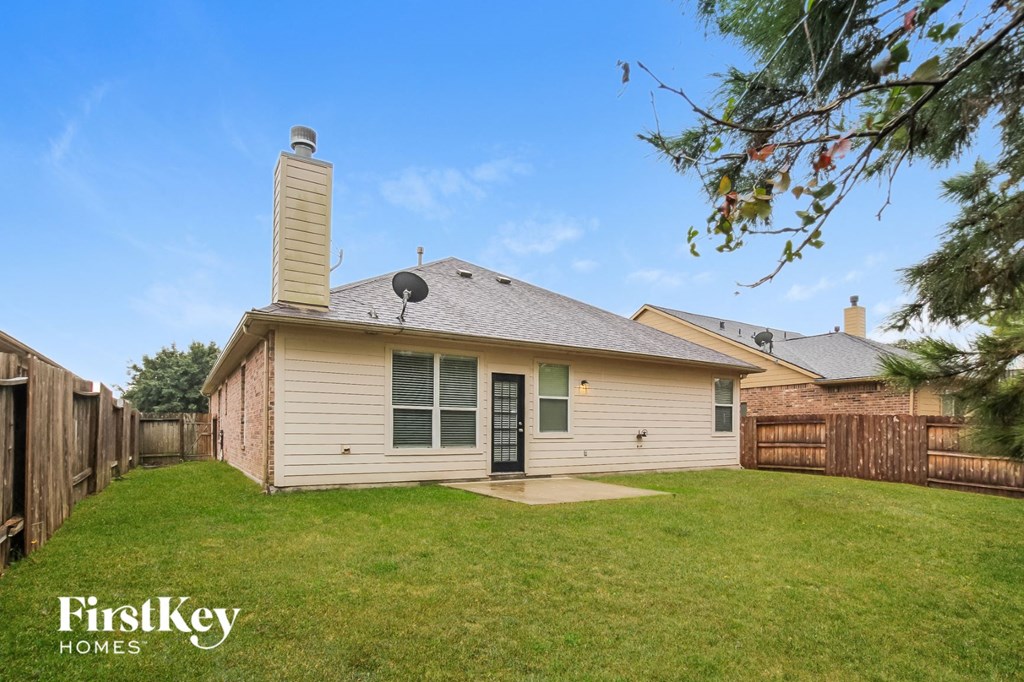 the backyard of a white house with a yard and a fence