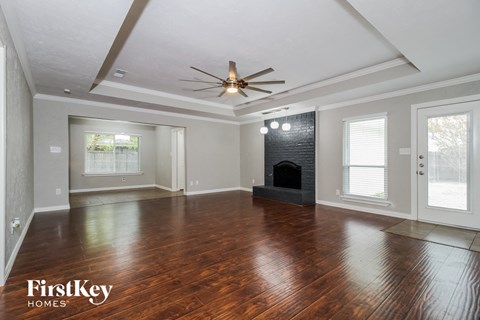 A spacious living room with wood flooring and a fireplace.