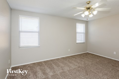 the spacious living room with carpet and a ceiling fan