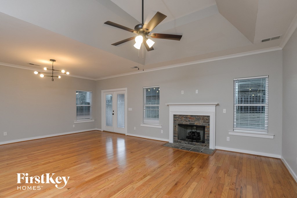 an empty living room with a fireplace and a ceiling fan