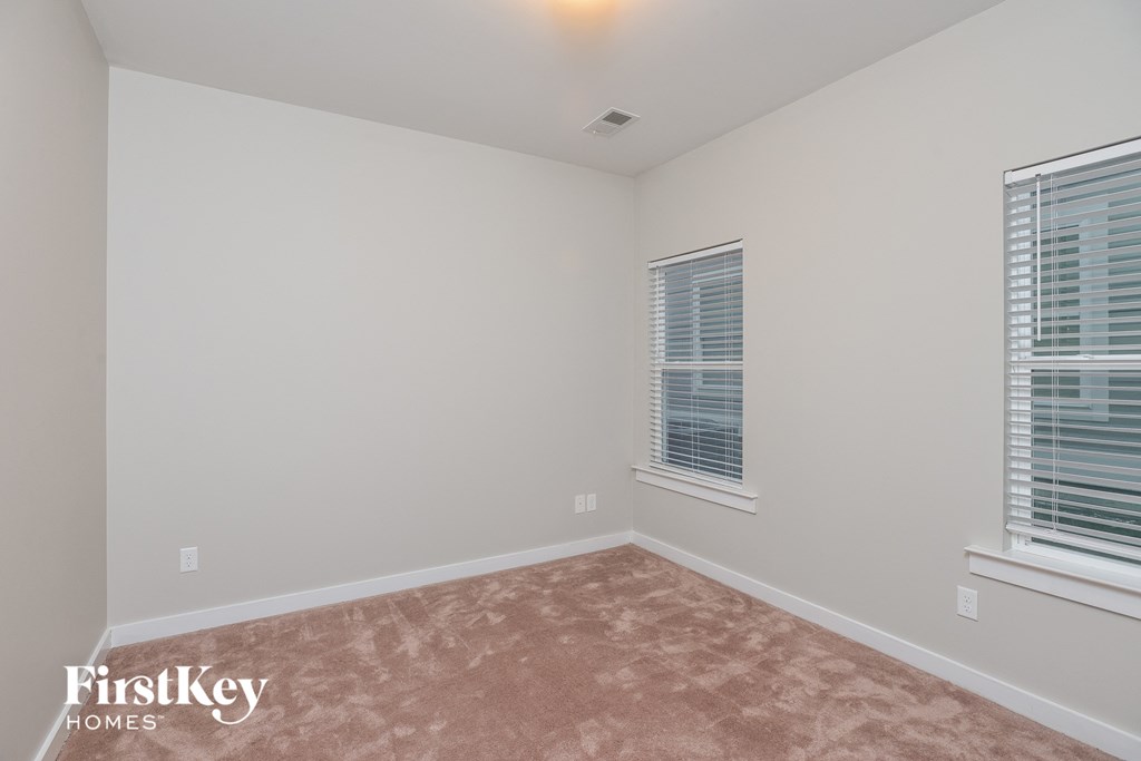 a bedroom with a carpeted floor and two windows