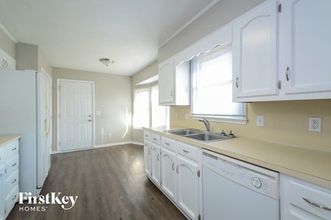 a kitchen with white cabinets and a sink and a window