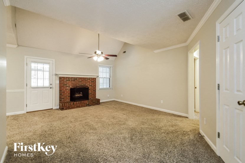 an empty living room with a fireplace and a ceiling fan