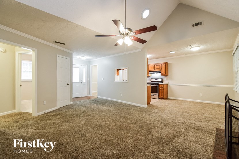 a spacious living room with carpet and a ceiling fan
