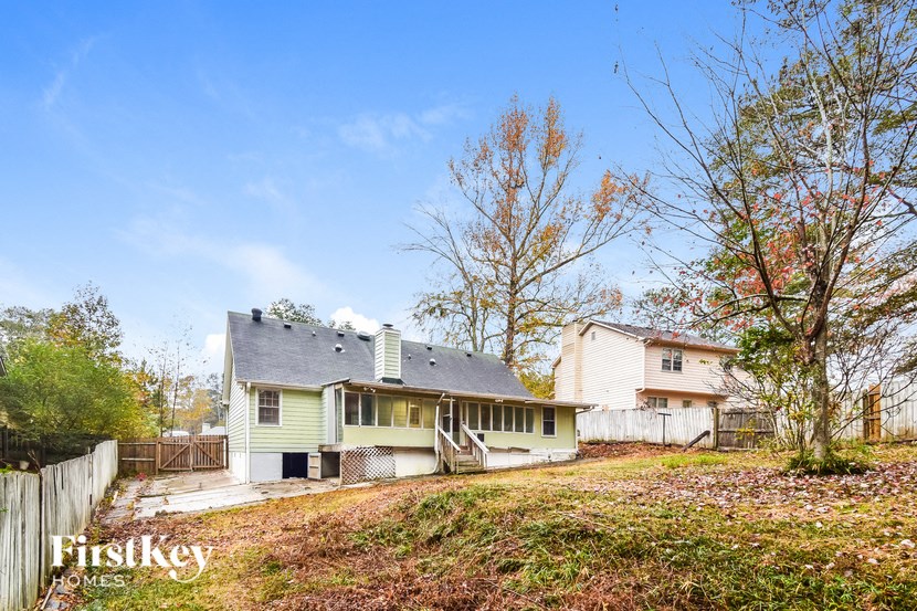the back of a white house with a yard and a fence