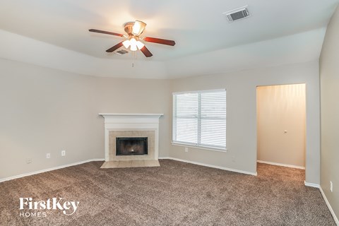 A living room with a fireplace and a ceiling fan.