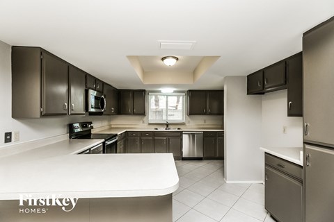 A kitchen with a white counter top and a window in the middle.