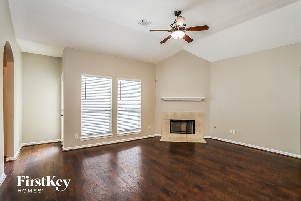 an empty living room with a ceiling fan and a fireplace