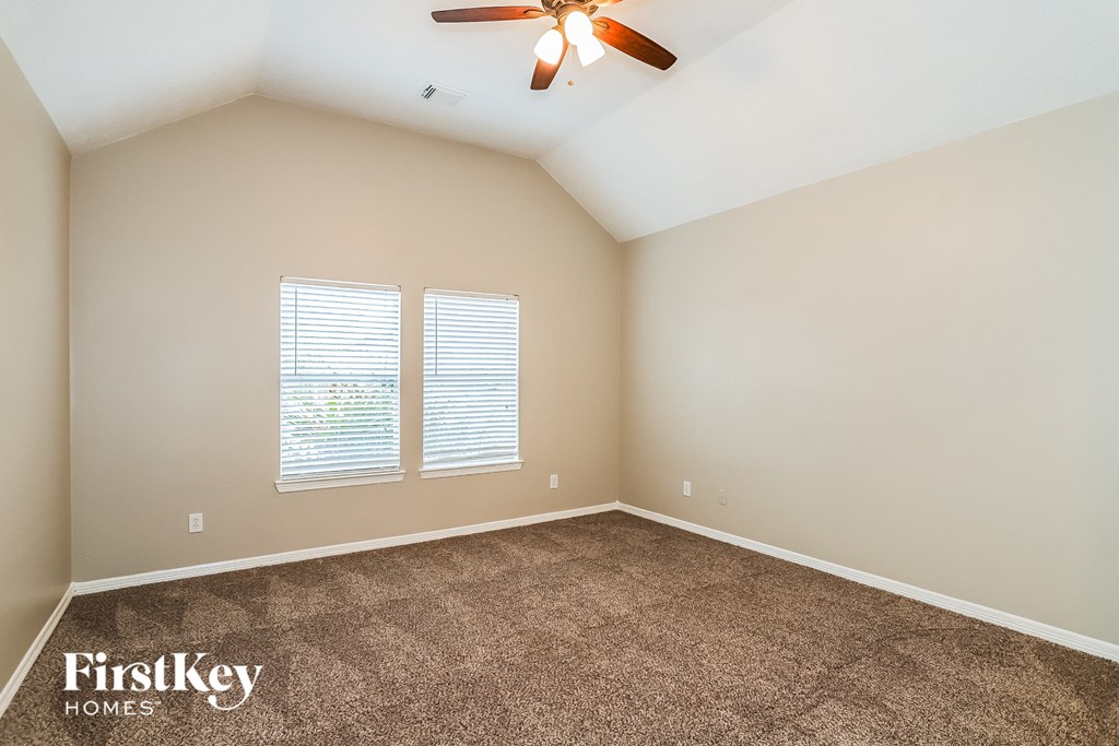 the master bedroom has a carpeted floor and a ceiling fan