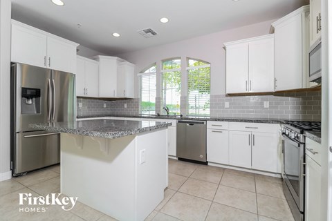 A kitchen with white cabinets and a stainless steel refrigerator.