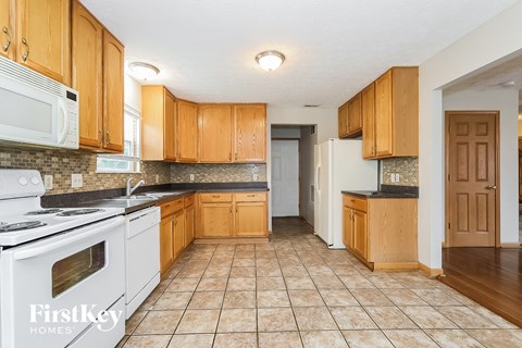 A kitchen with wooden cabinets and a white stove top oven.