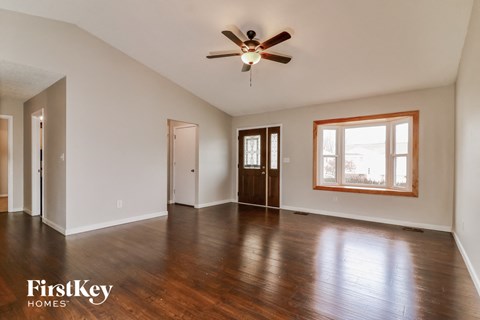 A spacious room with wooden floors and a ceiling fan.
