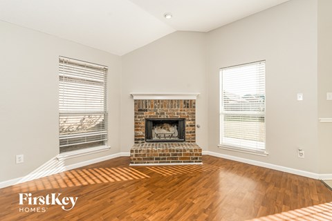 A living room with a fireplace and wooden floors.