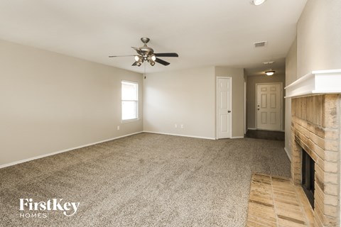 A spacious room with a fireplace and a ceiling fan.