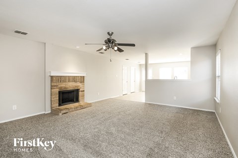 A spacious living room with a fireplace and a ceiling fan.