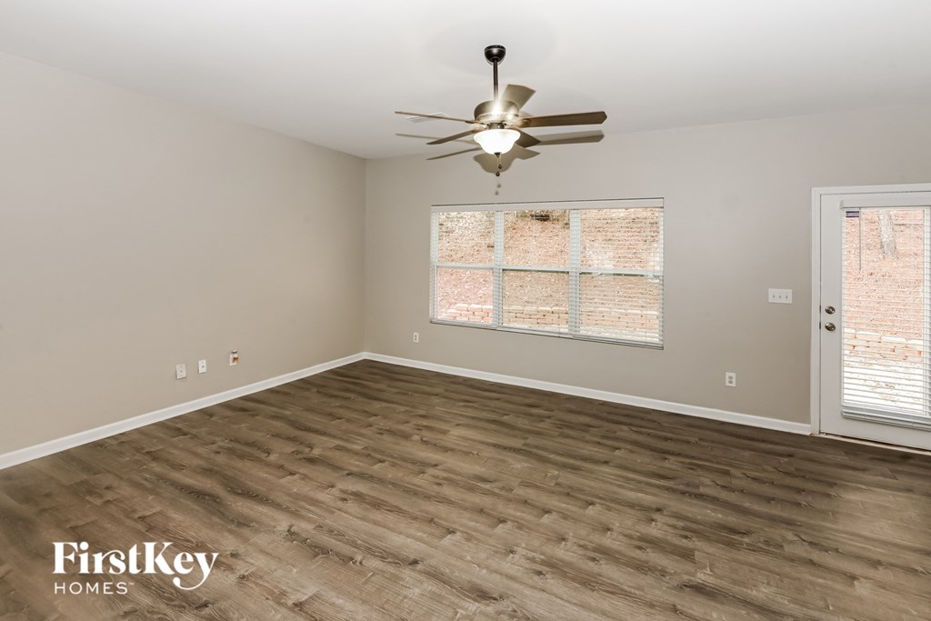 A room with a ceiling fan and wooden flooring.