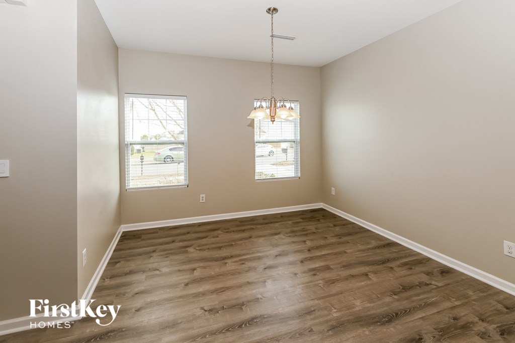A room with wooden flooring and two windows.