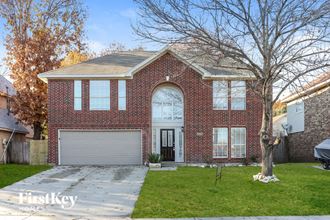 a brick house with a white garage door and a tree