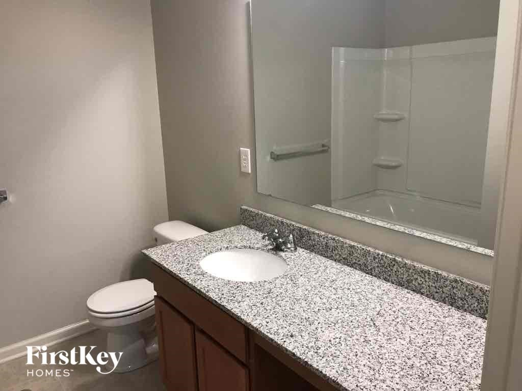 A bathroom with a granite countertop and a white toilet.