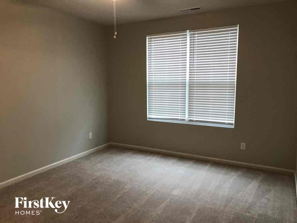 A room with a window covered in blinds and a carpet on the floor.