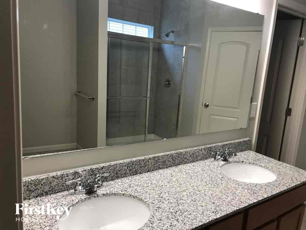 A bathroom with a granite countertop and two sinks.