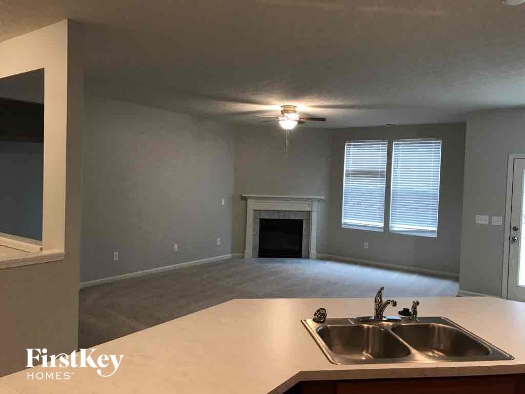 A kitchen with a sink and a fireplace in the background.