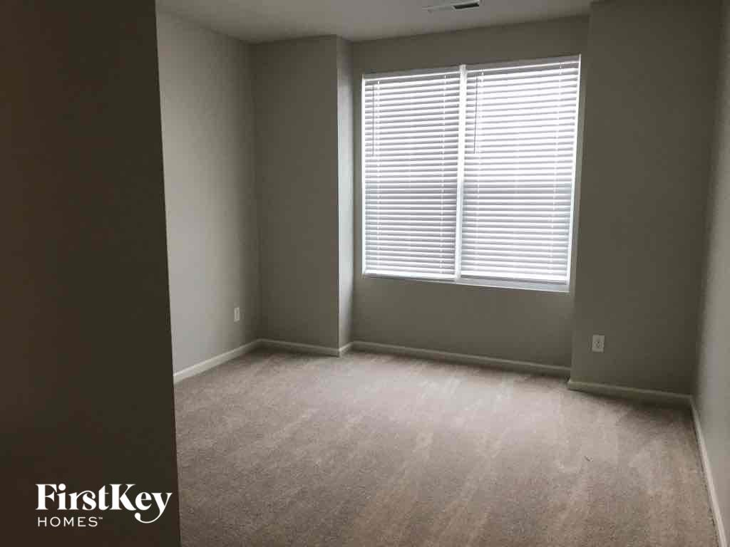 A room with a window covered by white blinds.