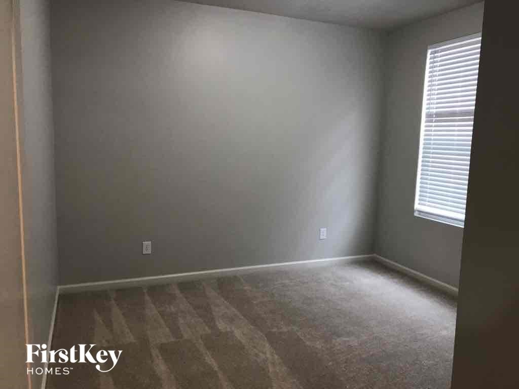 A room with a carpeted floor and a window with blinds.