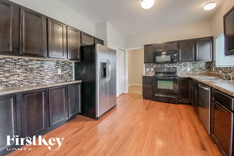 A kitchen with dark wood cabinets and a black refrigerator.