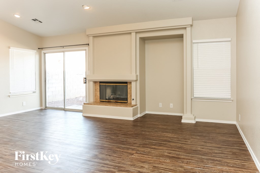 A large empty room with a fireplace and wooden floors.