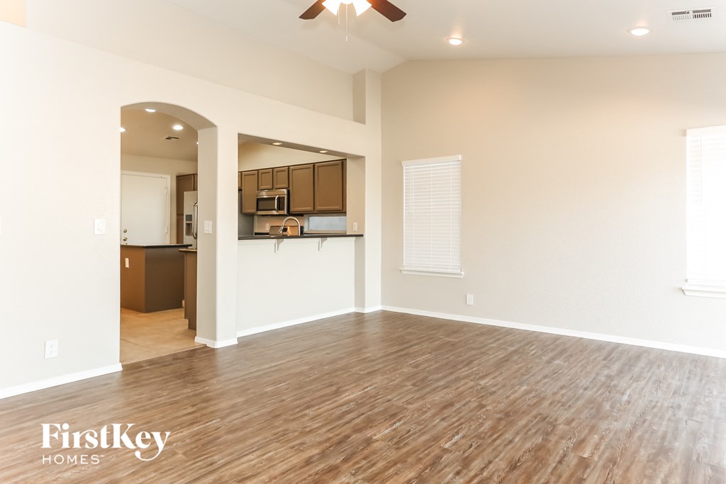 A spacious room with wooden flooring and a ceiling fan.