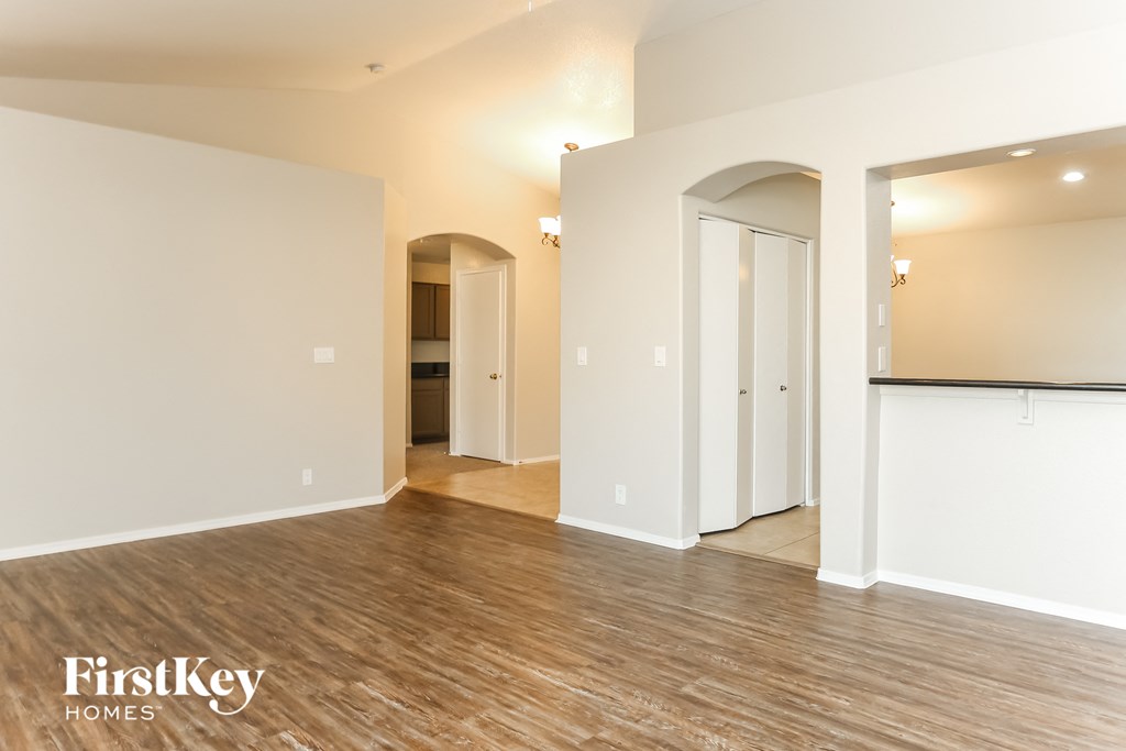 A spacious room with wooden flooring and white walls, with a doorway leading to another room.
