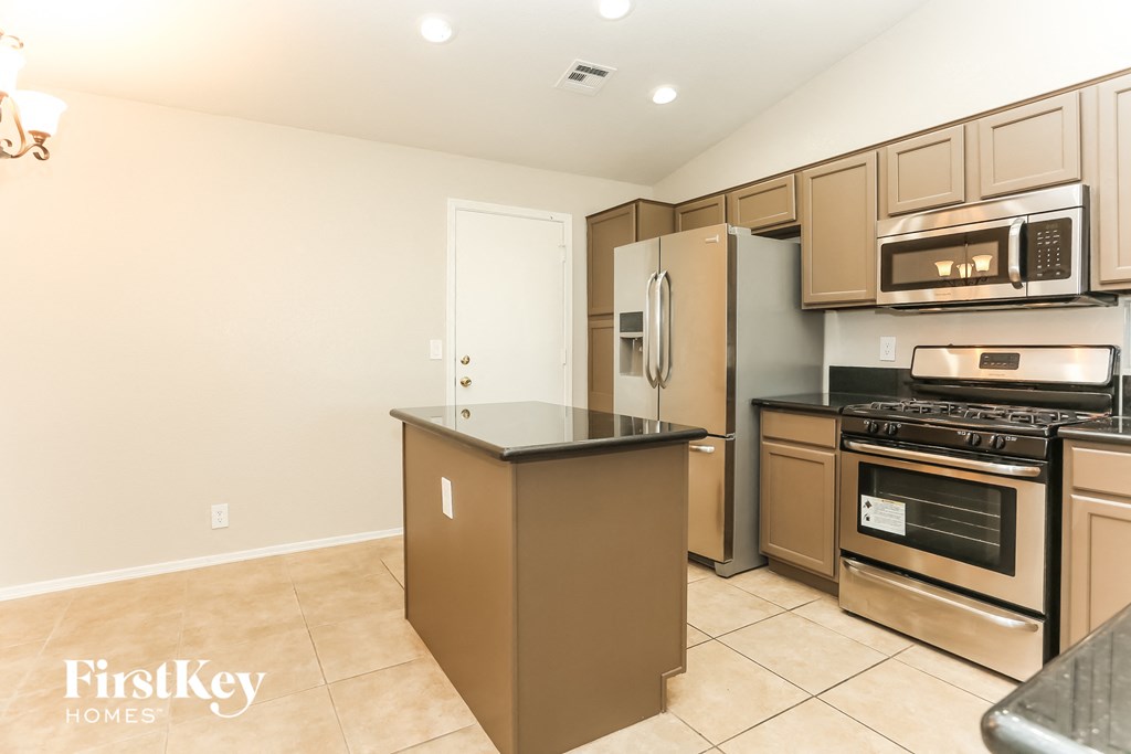 A kitchen with a brown island and stainless steel appliances.