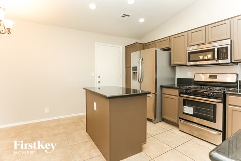A kitchen with a brown island and stainless steel appliances.
