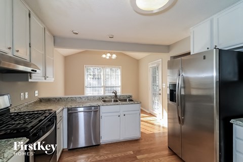 A kitchen with a stainless steel refrigerator and a black stove top oven.