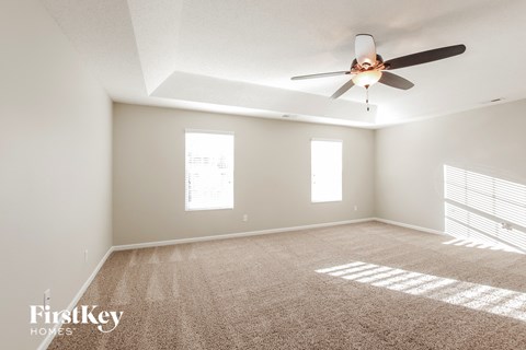 a living room with carpet and a ceiling fan